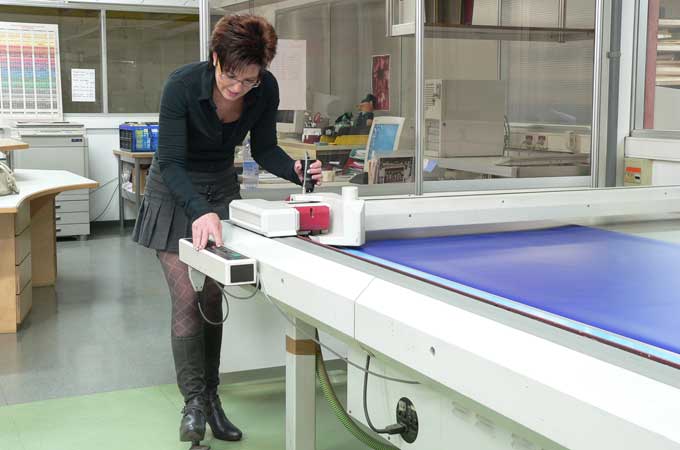 Eine Mitarbeiterin arbeitet aktiv an einen Folienschnitt an einer entsprechenden Maschine.